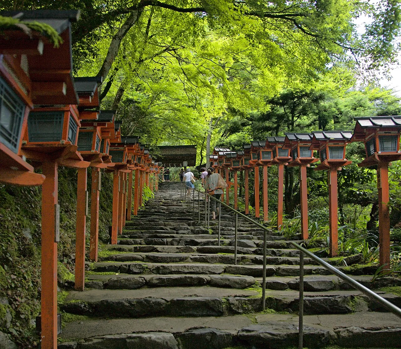 Stone steps and red lanterns beneath green trees at Kifune Shrine in Kyoto.